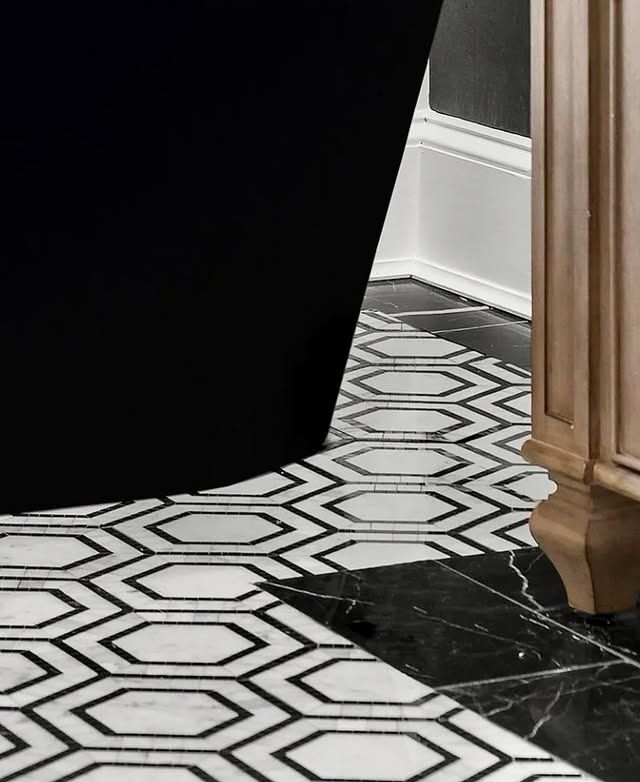 A bathroom with a black tub and a black and white tile floor.