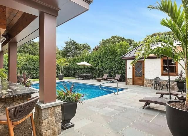 There is a large swimming pool in the backyard of a house.