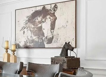 A living room with a painting of a horse on the wall.