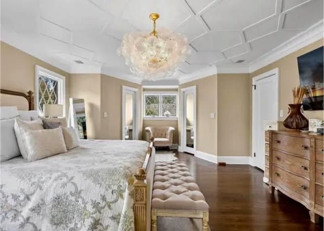 A bedroom with two beds , a bench , a dresser and a chandelier.