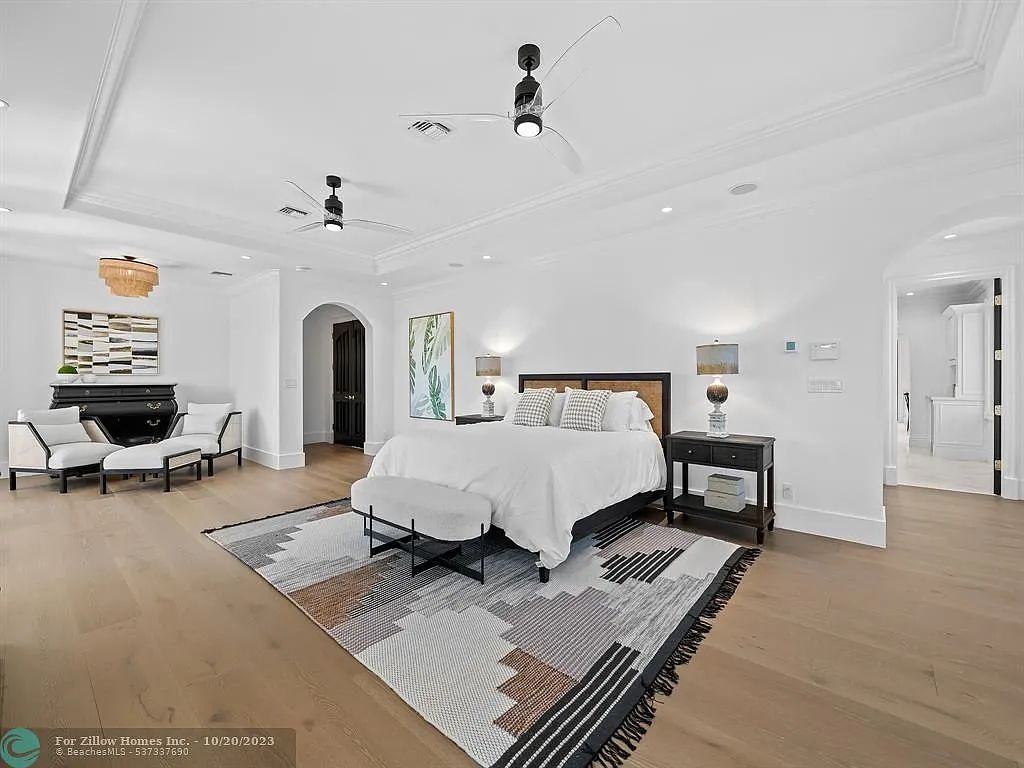 A large bedroom with a king size bed , a rug , and a ceiling fan.