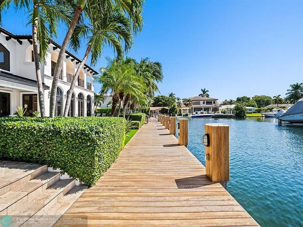 A wooden dock leading to a house next to a body of water.