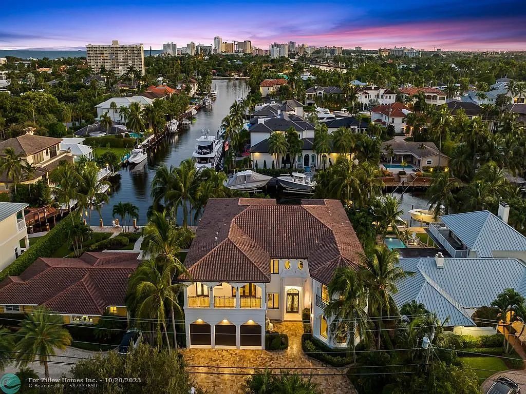 An aerial view of a large house surrounded by palm trees in a residential area.