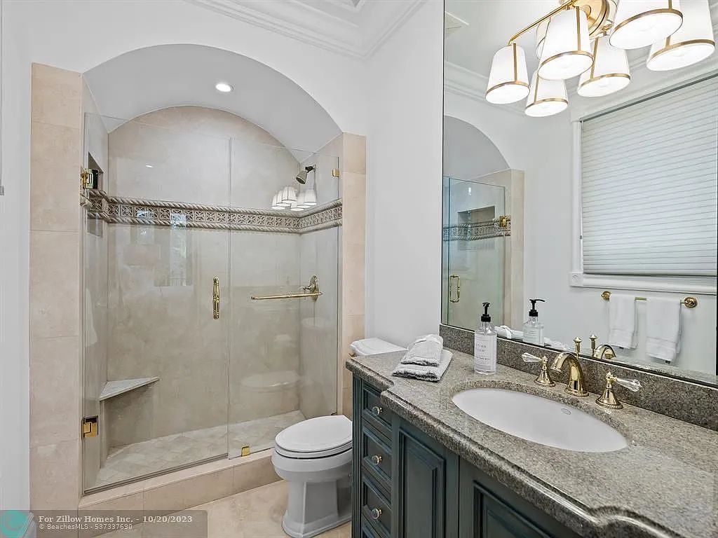 A bathroom with a toilet , sink , shower and mirror.