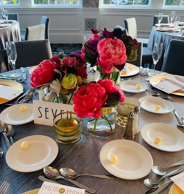 A table setting with a vase of flowers and a sign that says seven