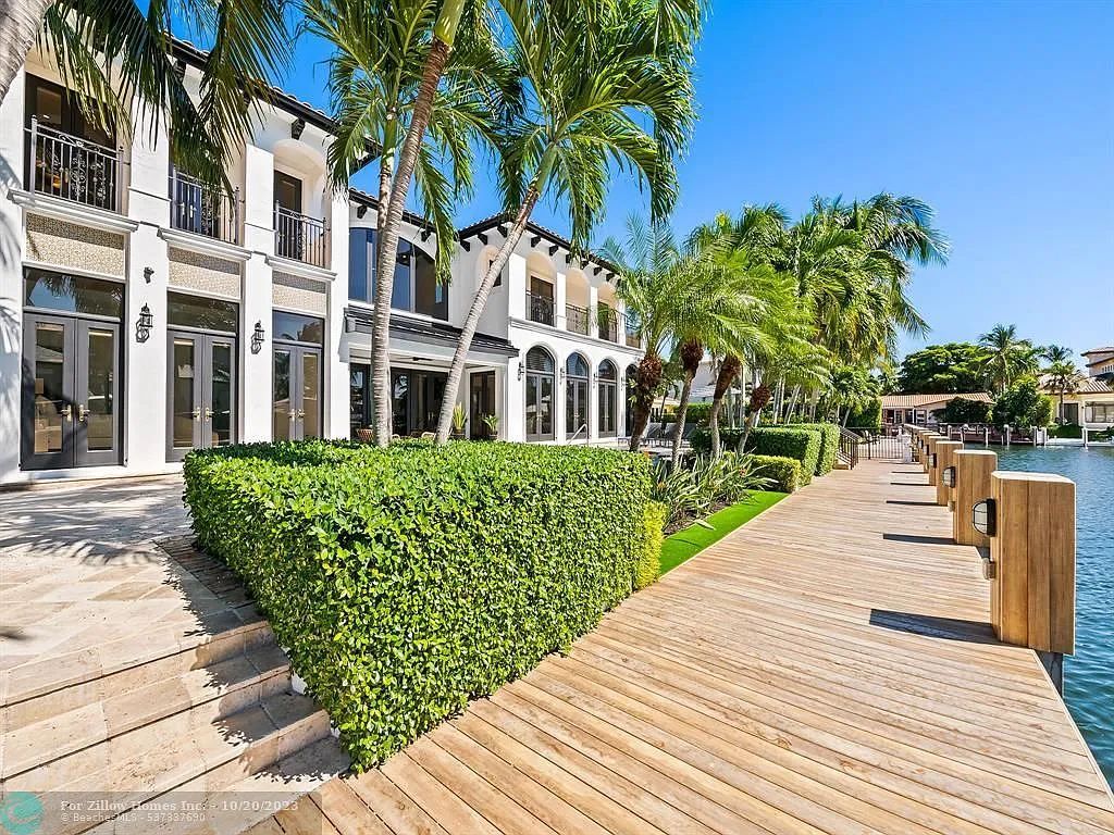 A large white house with a wooden dock in front of it.