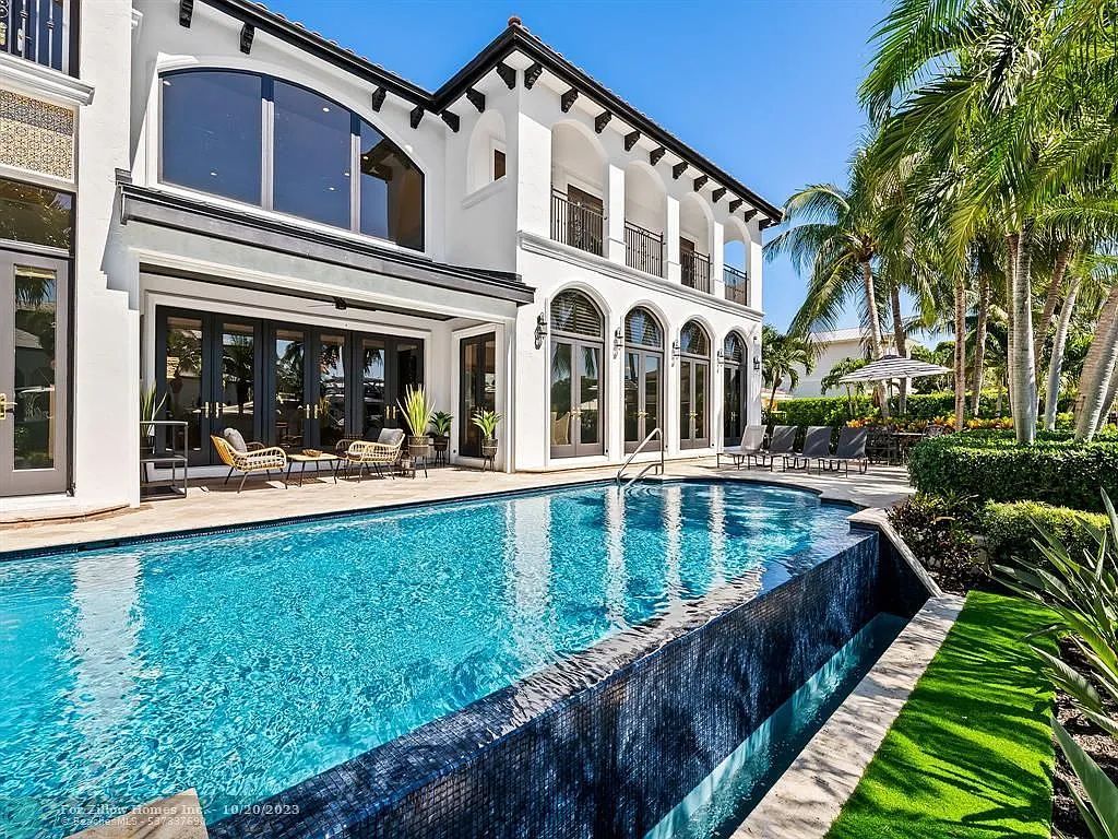 A large white house with a large swimming pool in front of it.