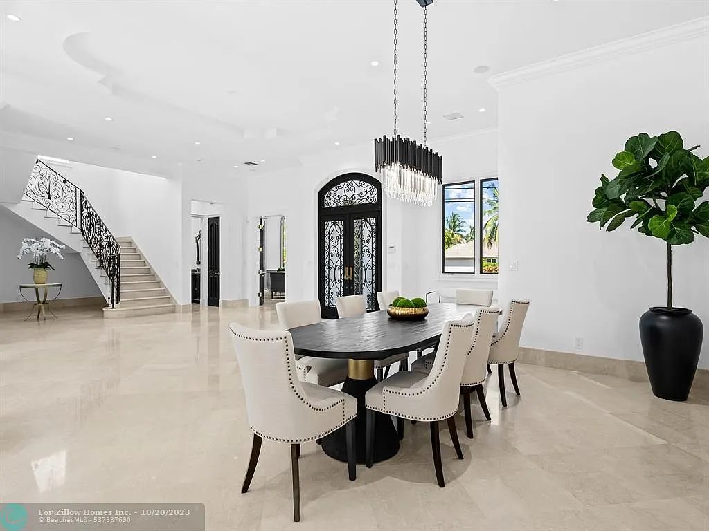 A dining room with a table and chairs and a plant.