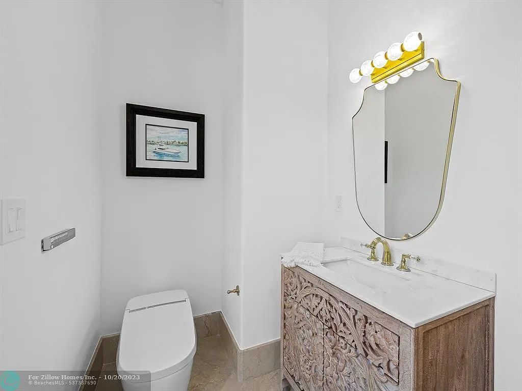 A bathroom with a toilet , sink , mirror and picture on the wall.