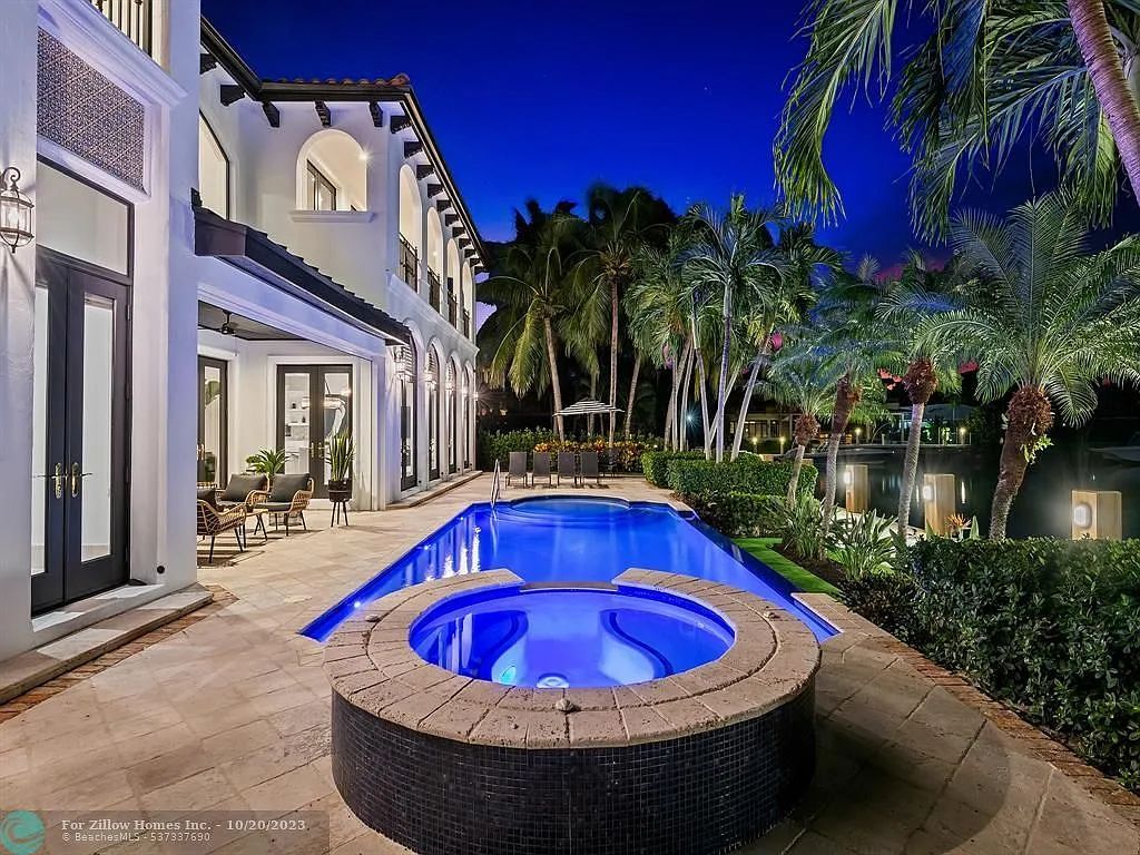 A large house with a swimming pool and a hot tub in front of it.