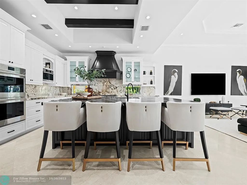 A kitchen with a large island , stools and a television.