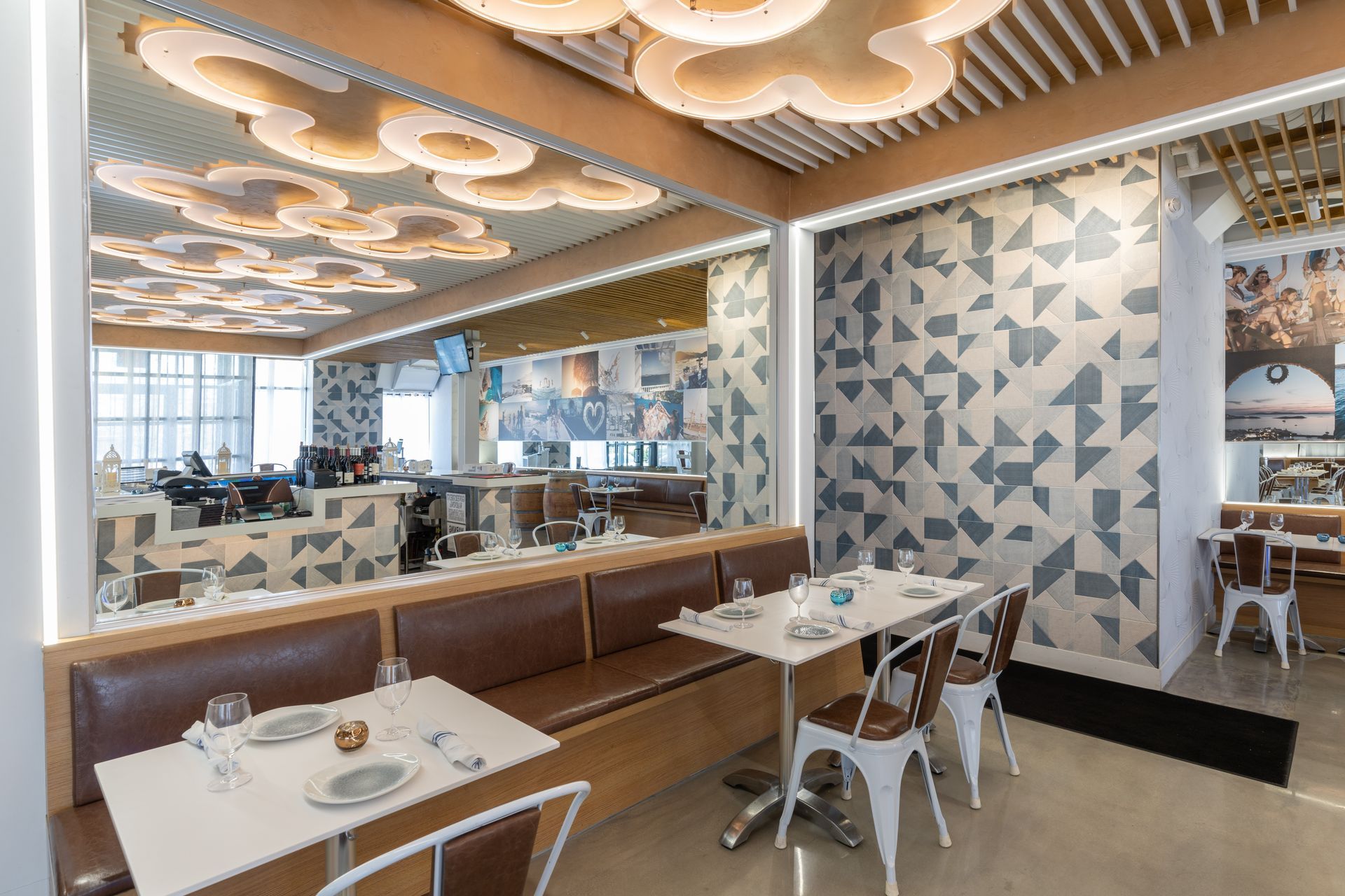 A restaurant with tables and chairs and a geometric wall.