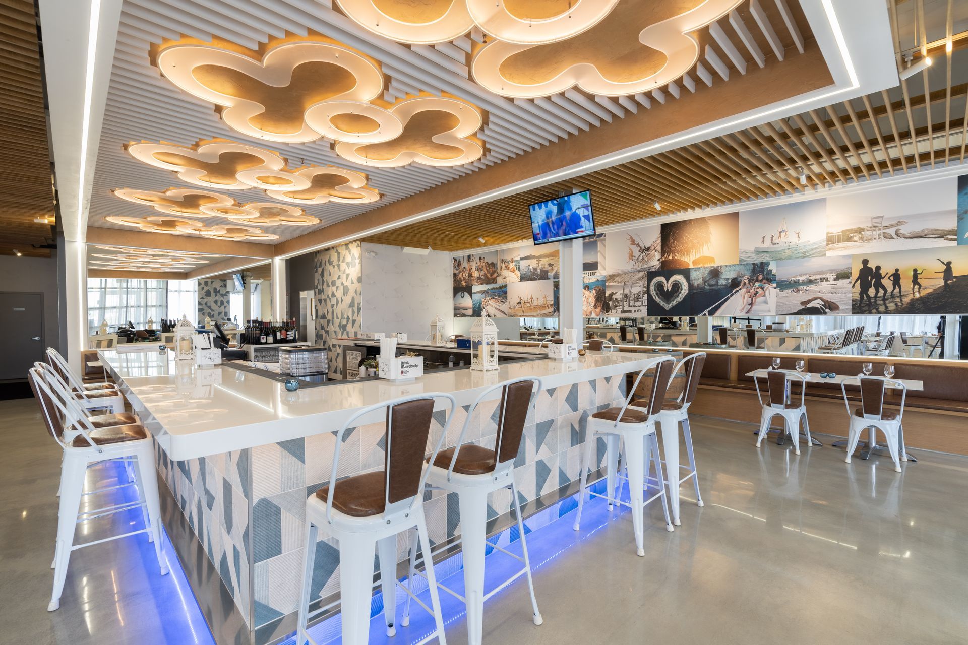 A restaurant with a long bar and tables and chairs.