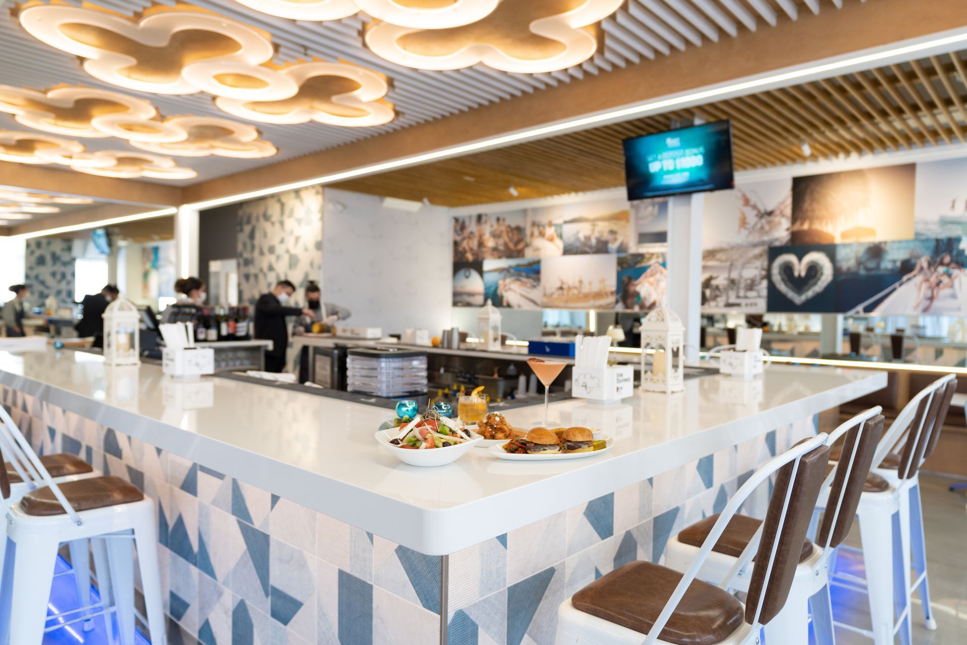 A restaurant with a long bar and stools and a plate of food on the counter.