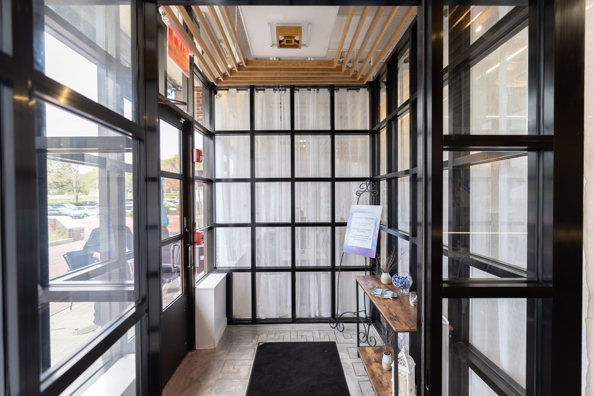 A hallway with a lot of windows and a black mat on the floor.
