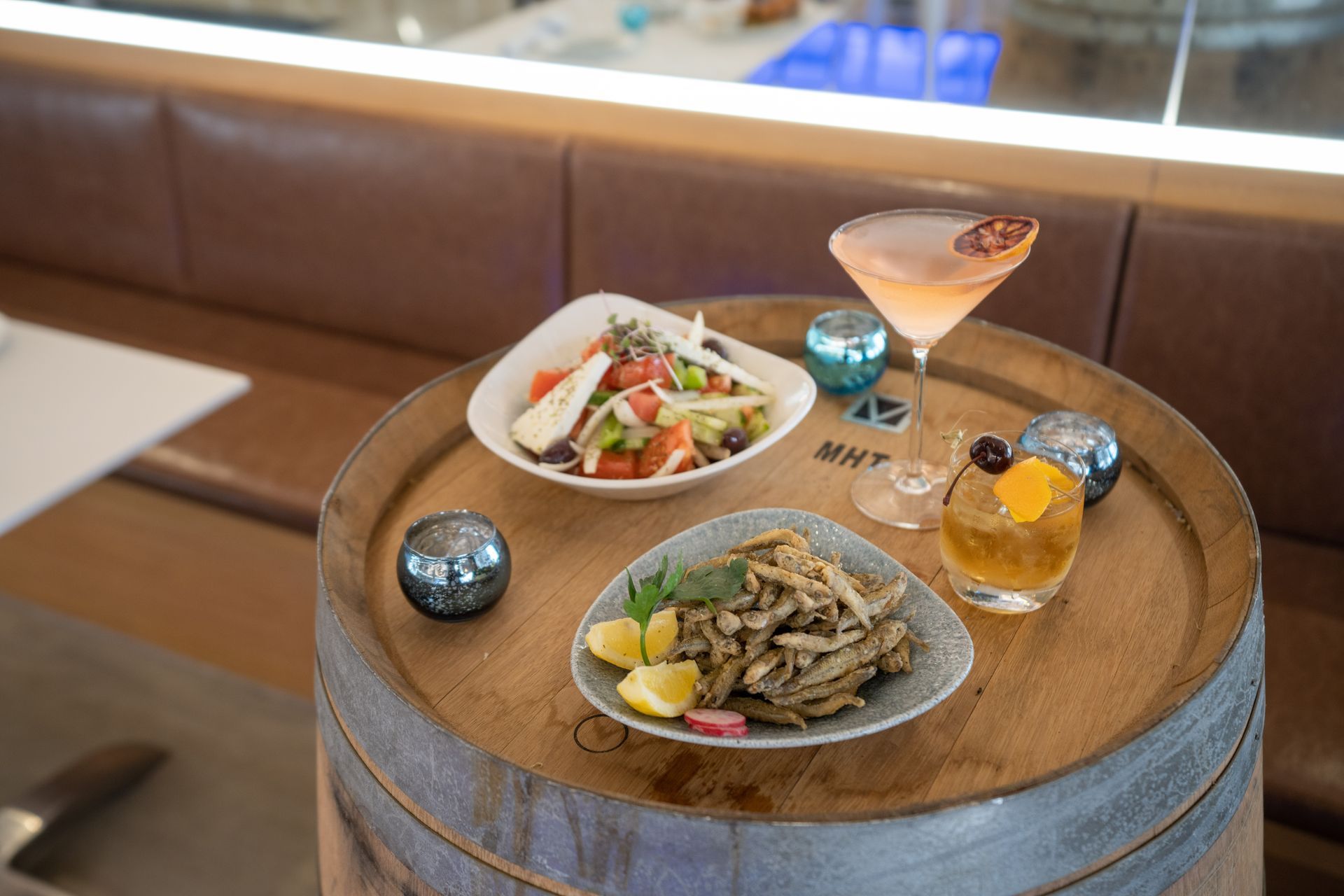 A wooden barrel with plates of food and drinks on it.