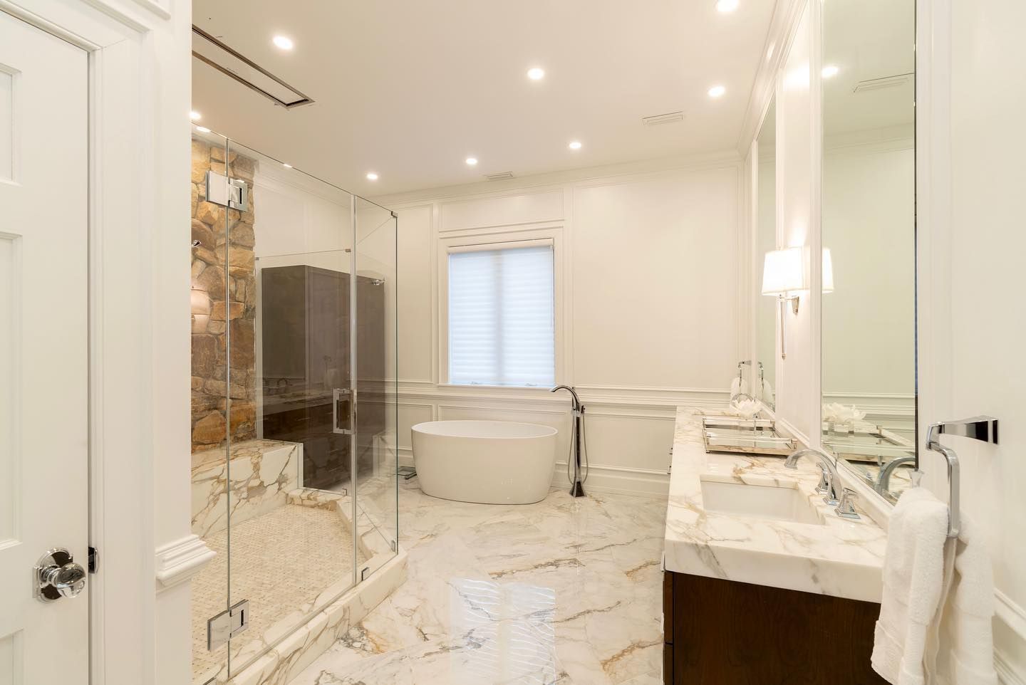 A bathroom with a tub , sink , mirror and walk in shower.