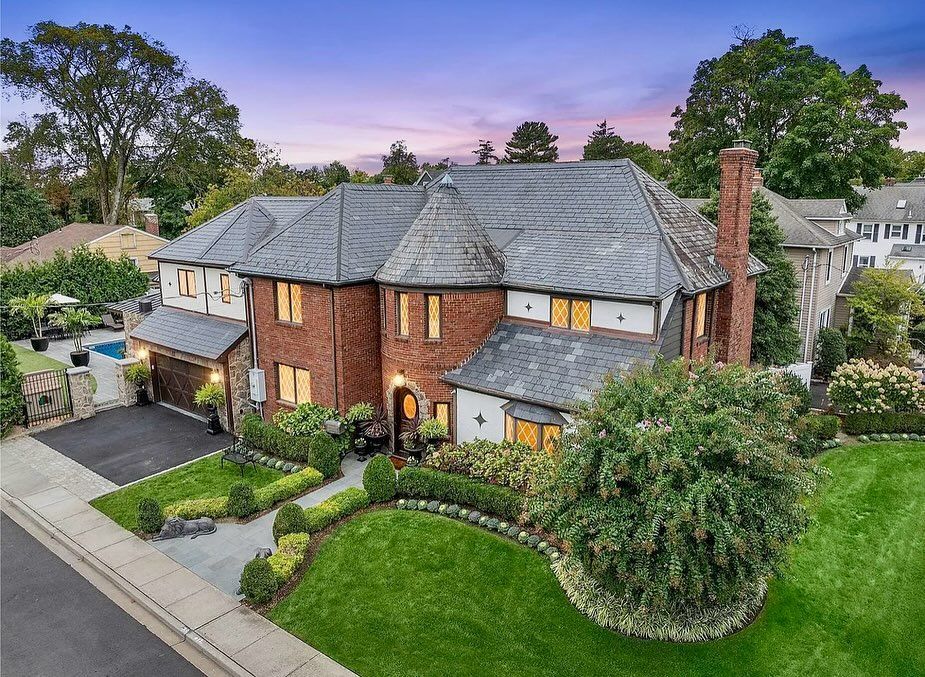 An aerial view of a large brick house with a lush green lawn.