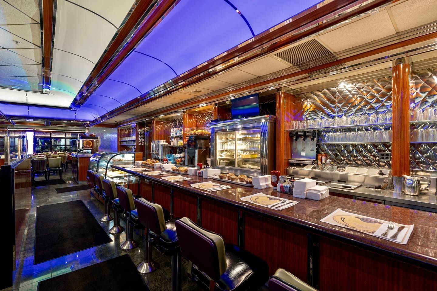 A restaurant with a long bar and a lot of chairs.