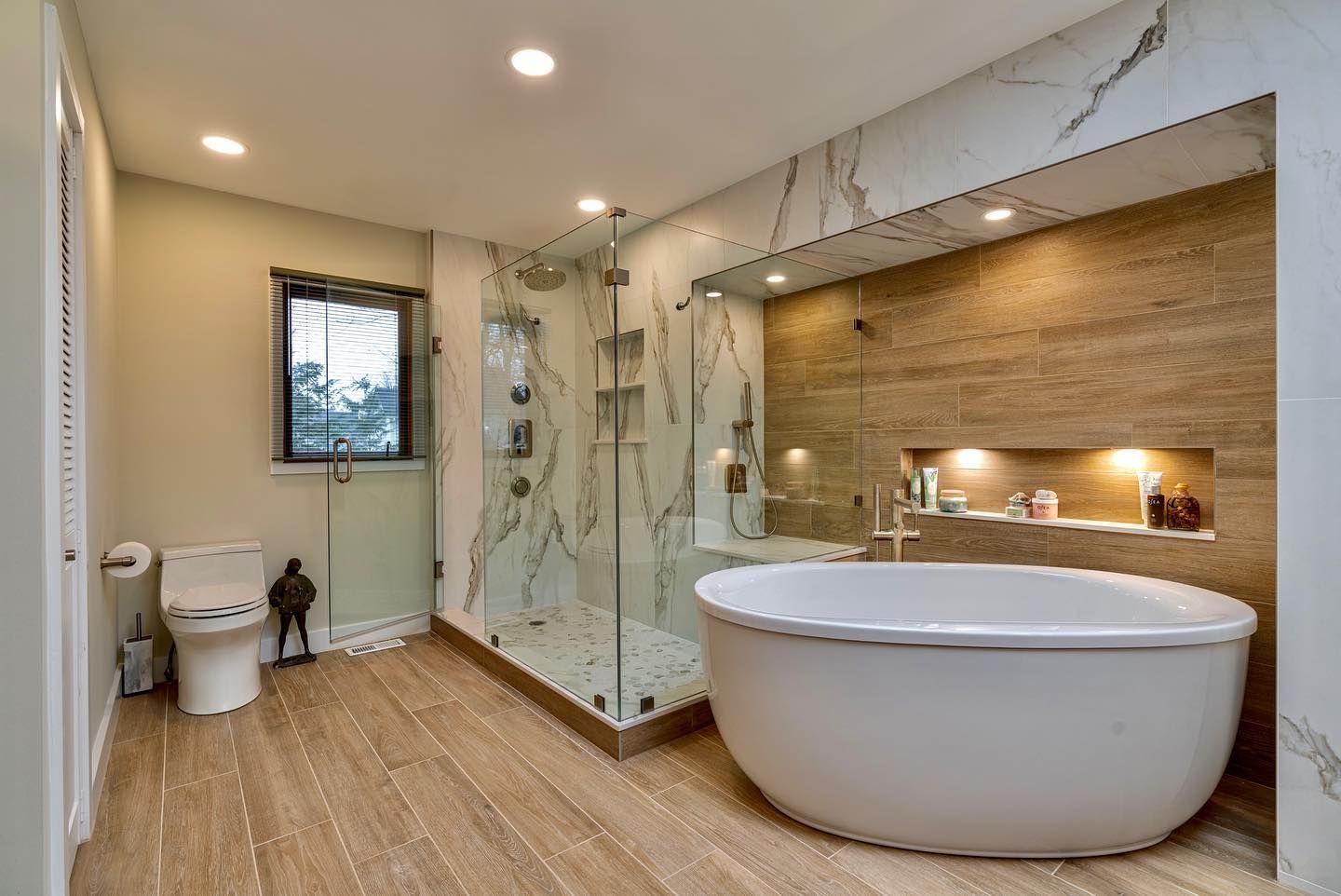 A bathroom with a tub , toilet , shower and window.