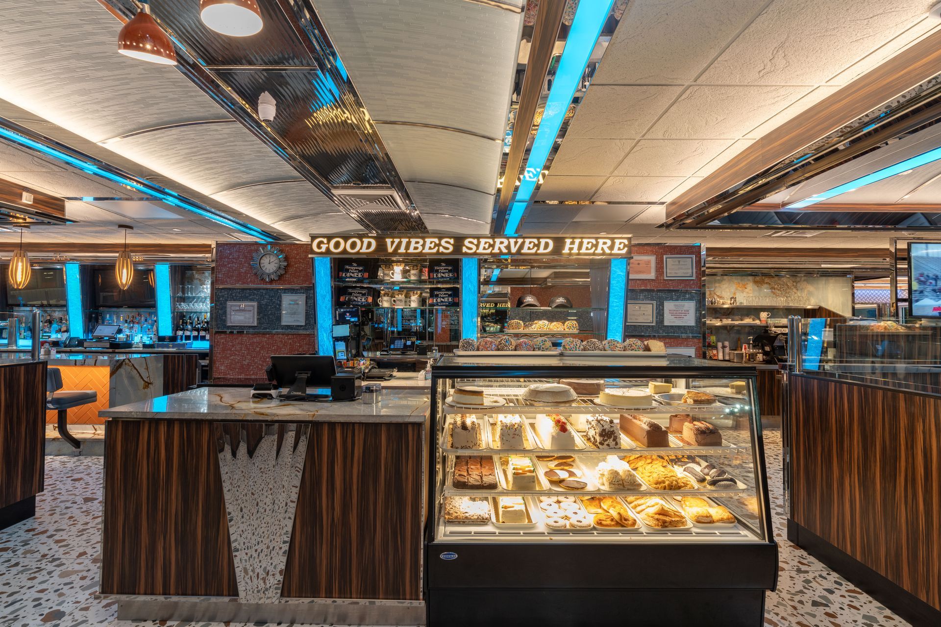 A restaurant with a display case filled with food and a sign that says `` good vibes served here ''.