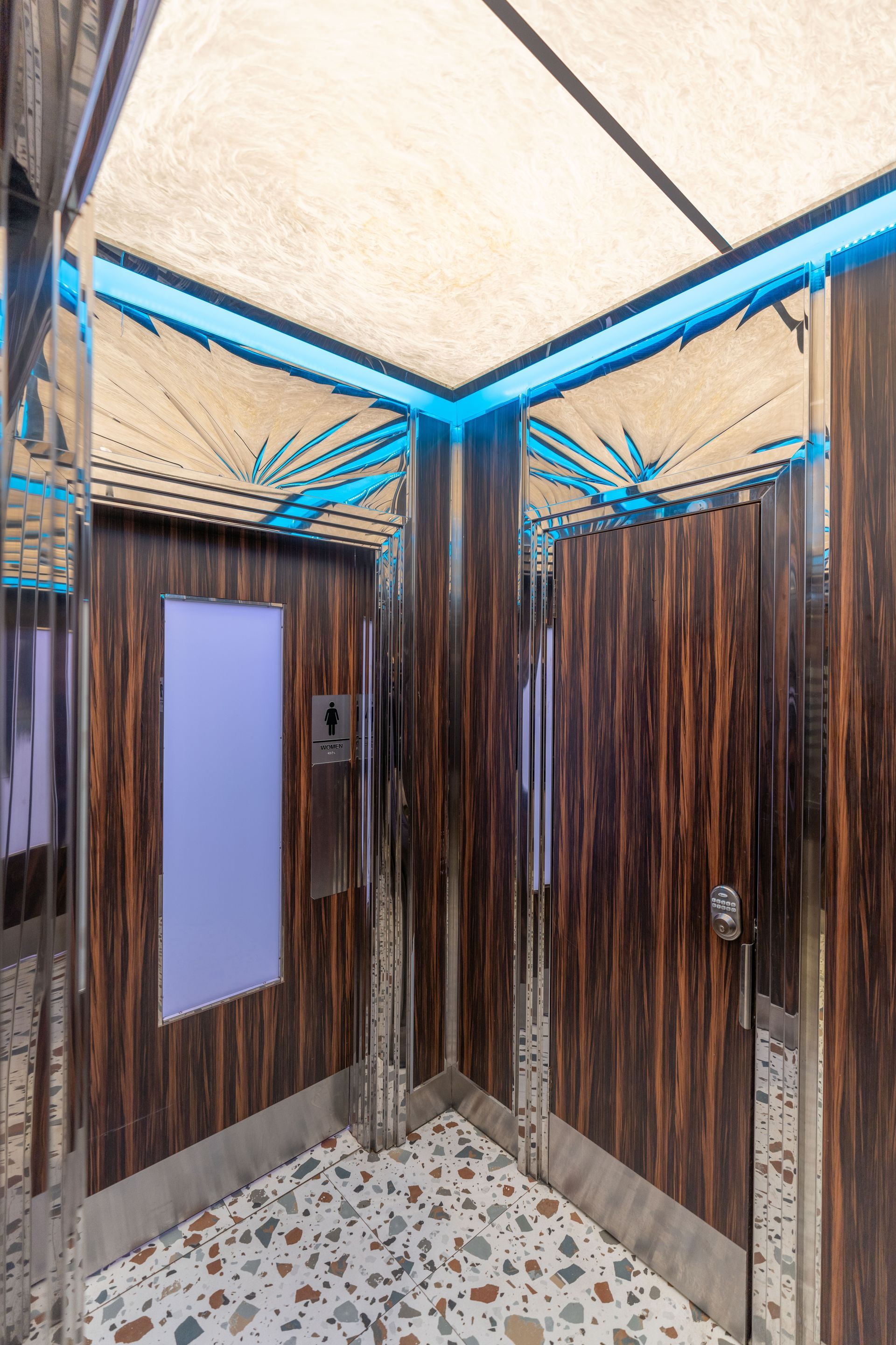 A bathroom with wooden walls and a mirrored floor.