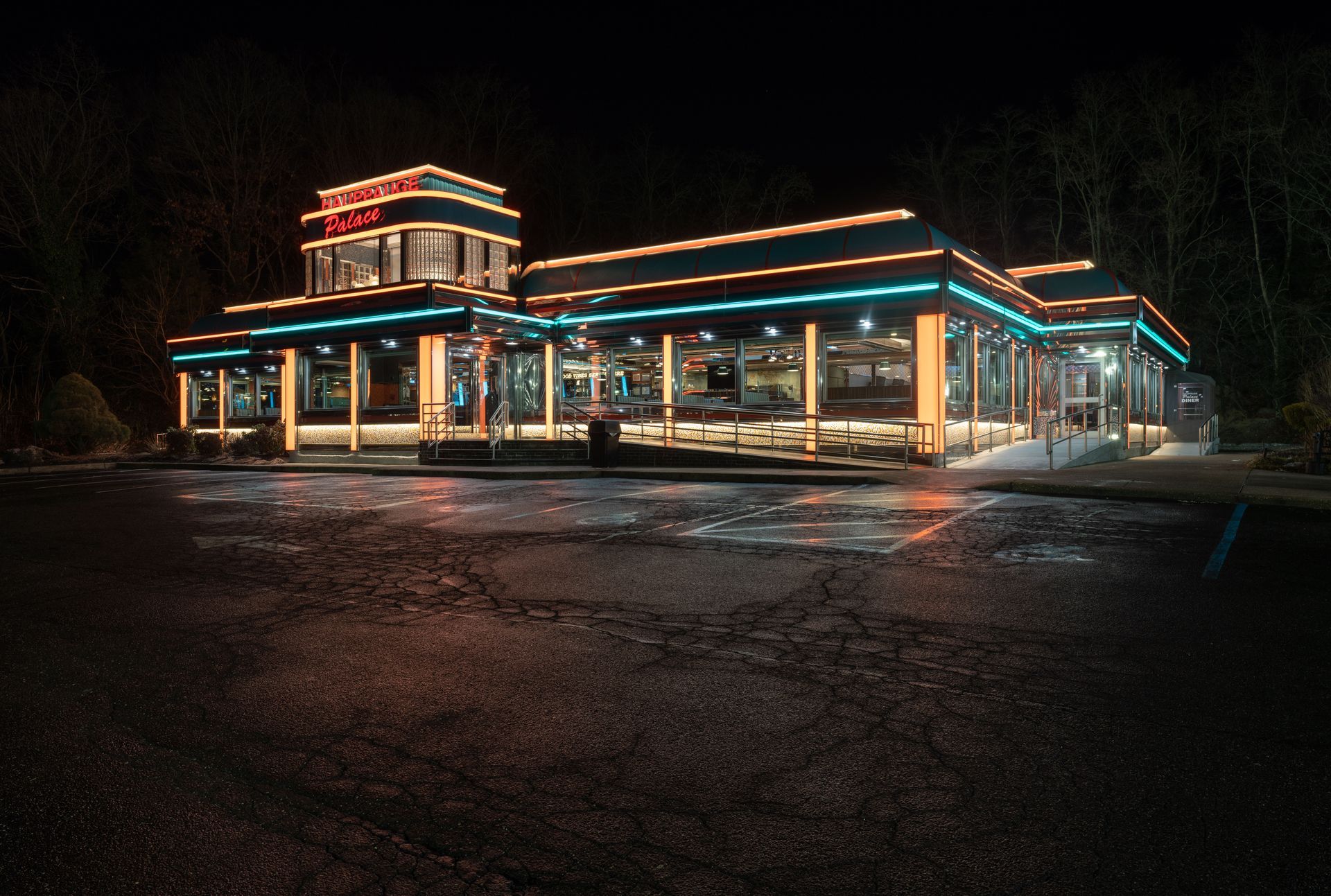A diner is lit up at night with a parking lot in front of it.