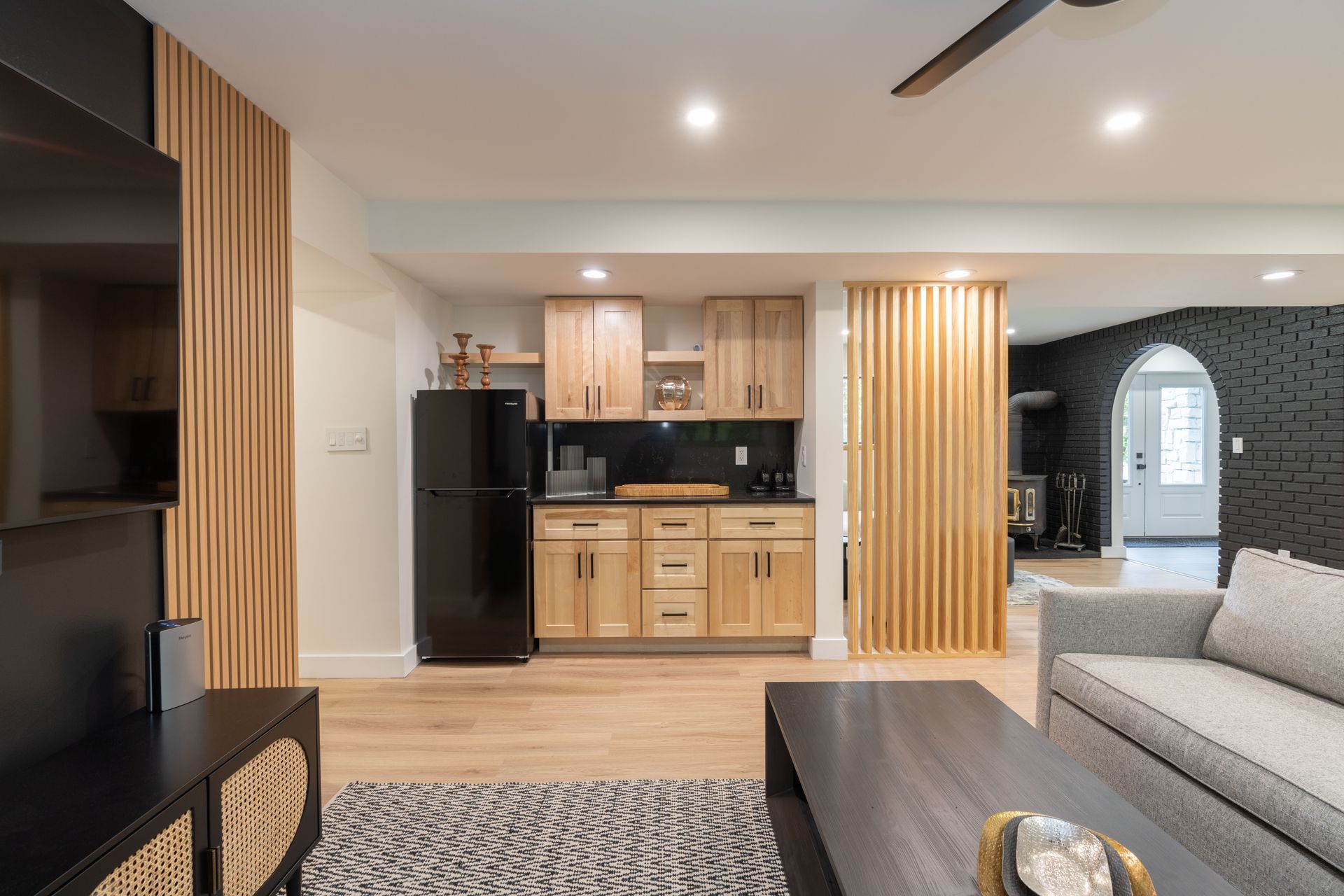 A living room with a couch , coffee table , television and refrigerator.