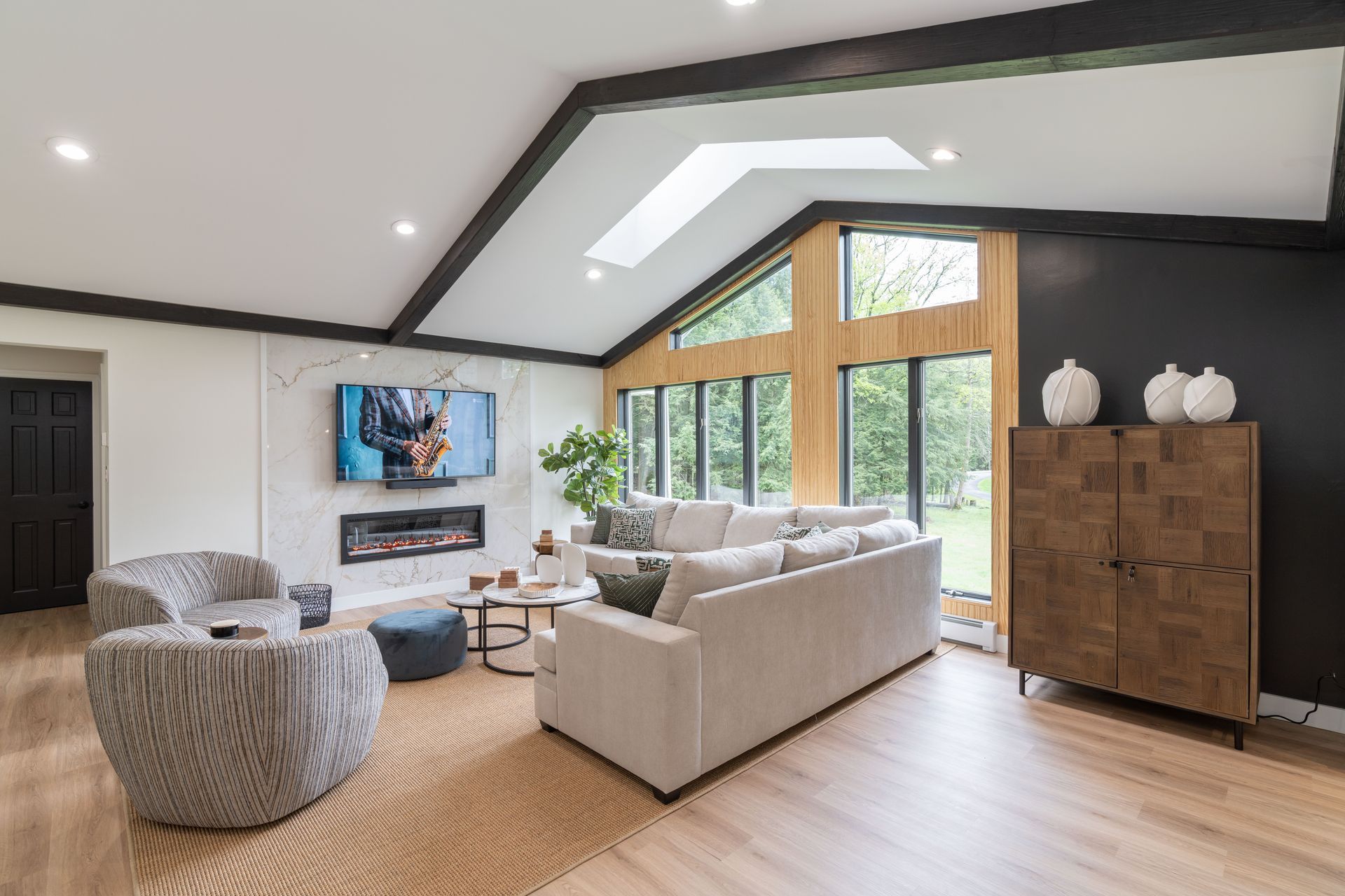 A living room with a couch , chairs , and a flat screen tv.