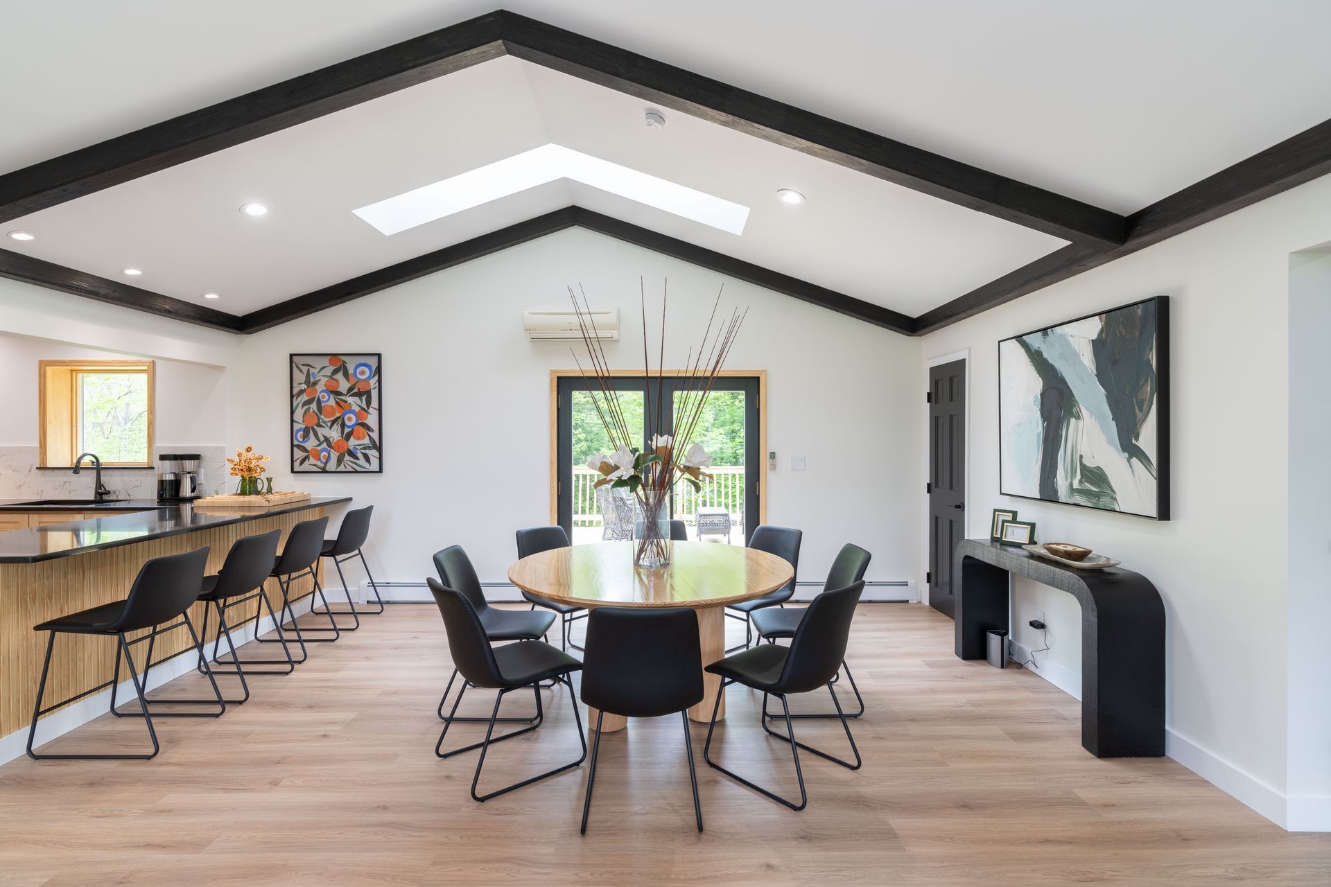A dining room with a round table and chairs and a vaulted ceiling.