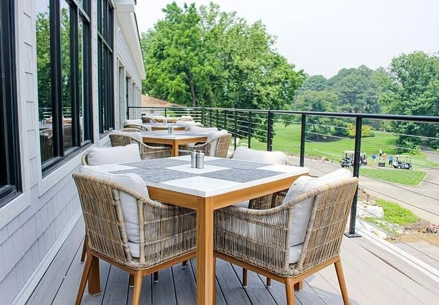 A table and chairs on a balcony overlooking a golf course.