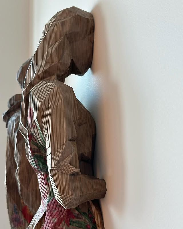 A cardboard sculpture of a woman leaning against a wall