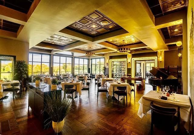 A large dining room with tables and chairs and a piano.