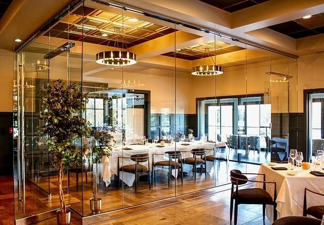 A restaurant with tables and chairs and a glass wall