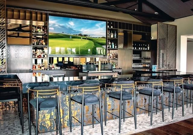 A bar with a large screen on the wall above it