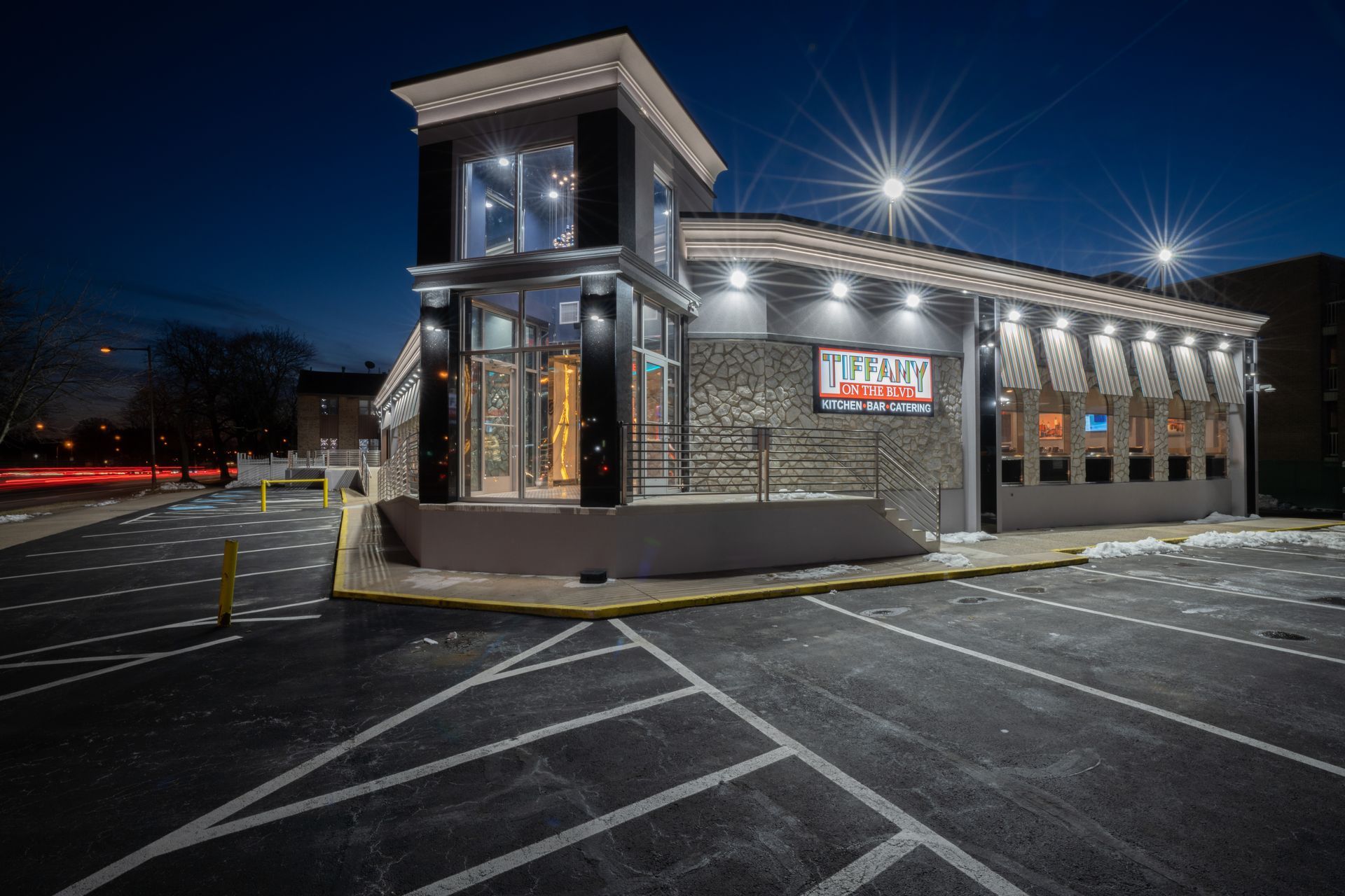 A large building with a parking lot in front of it at night.