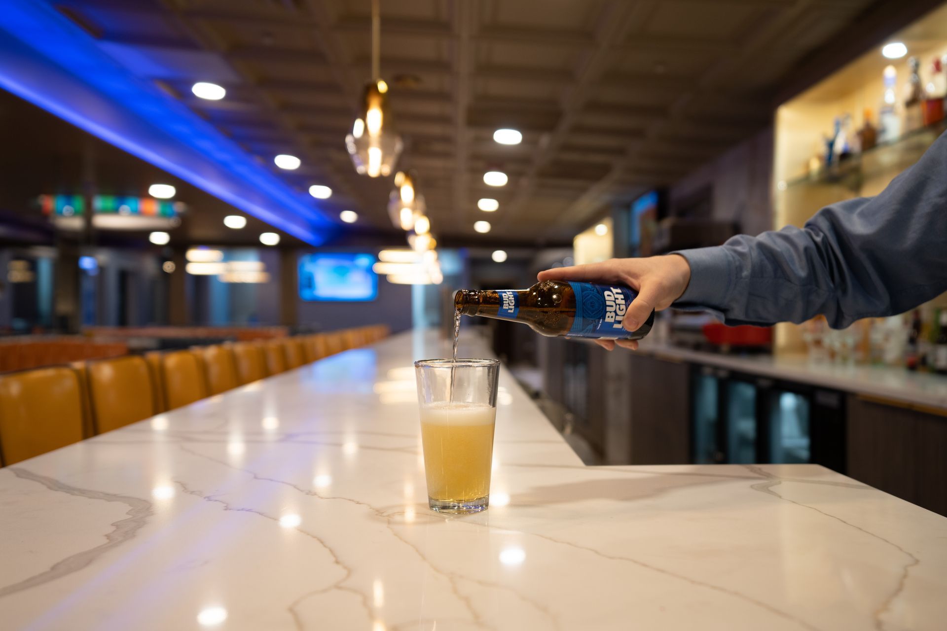 A person is pouring a beer into a glass at a bar.