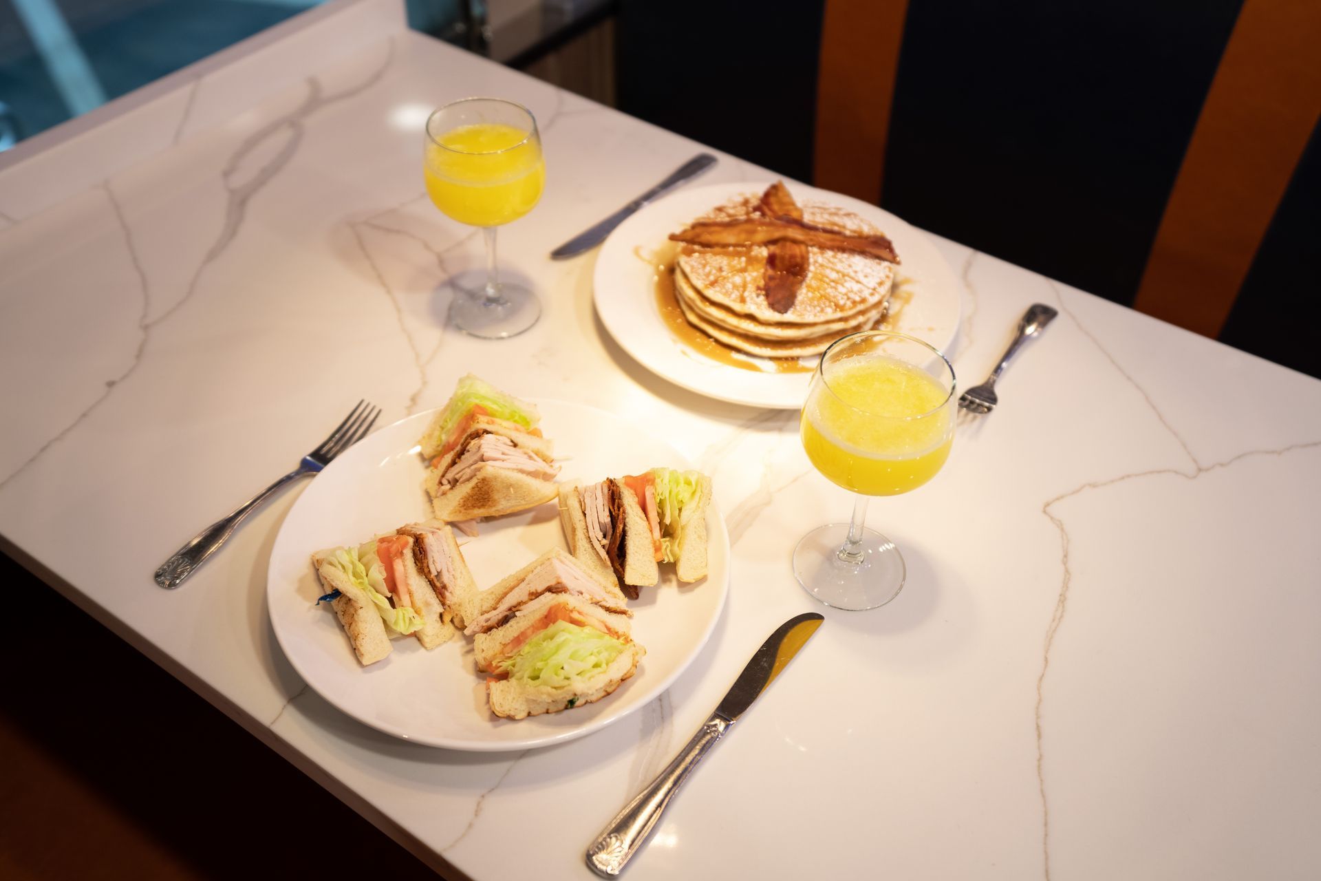 A table topped with plates of food including pancakes and sandwiches.