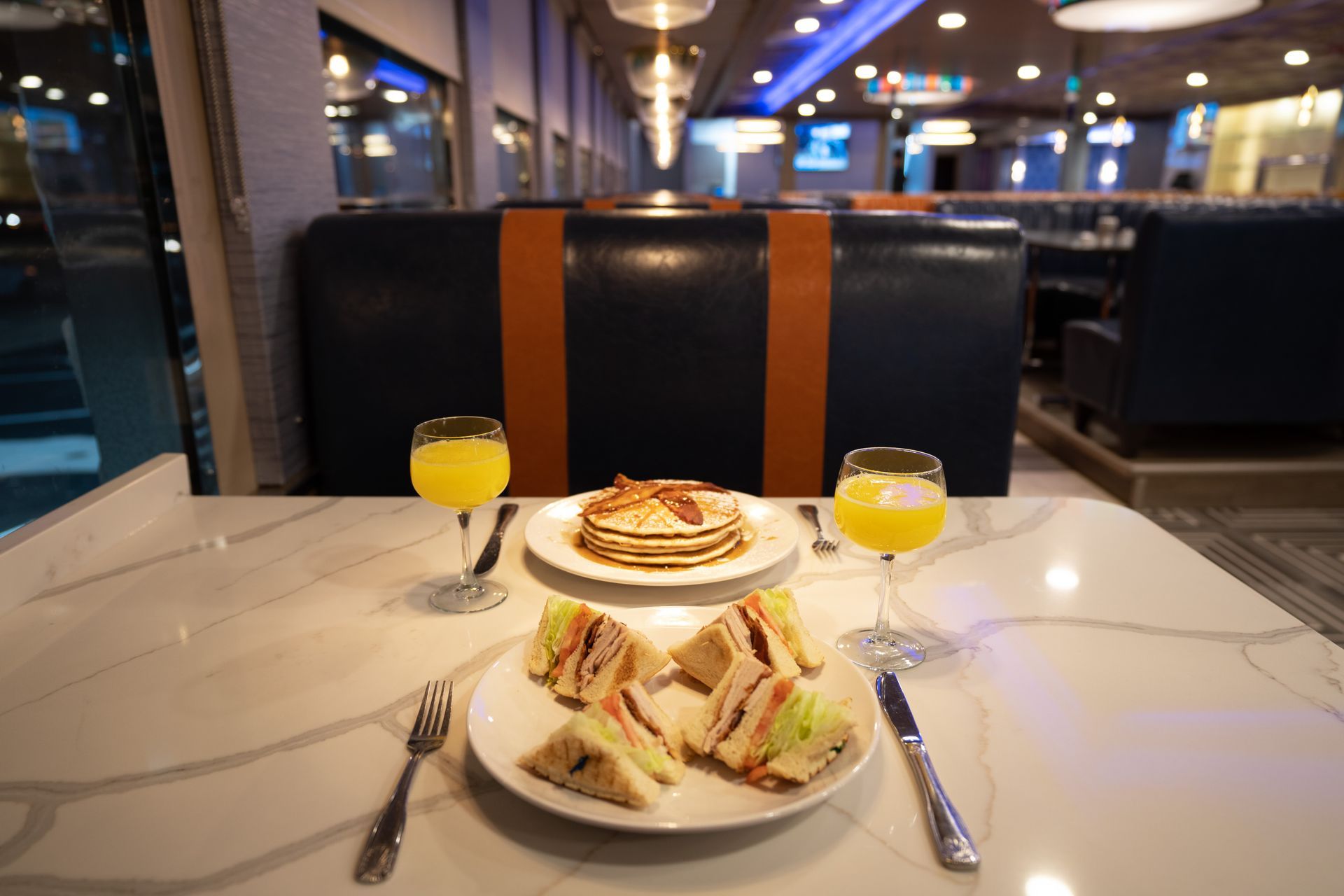 A table with two plates of food and two glasses of orange juice.