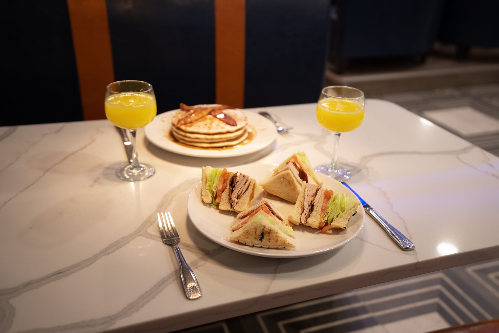 Two plates of food and two glasses of orange juice on a table.