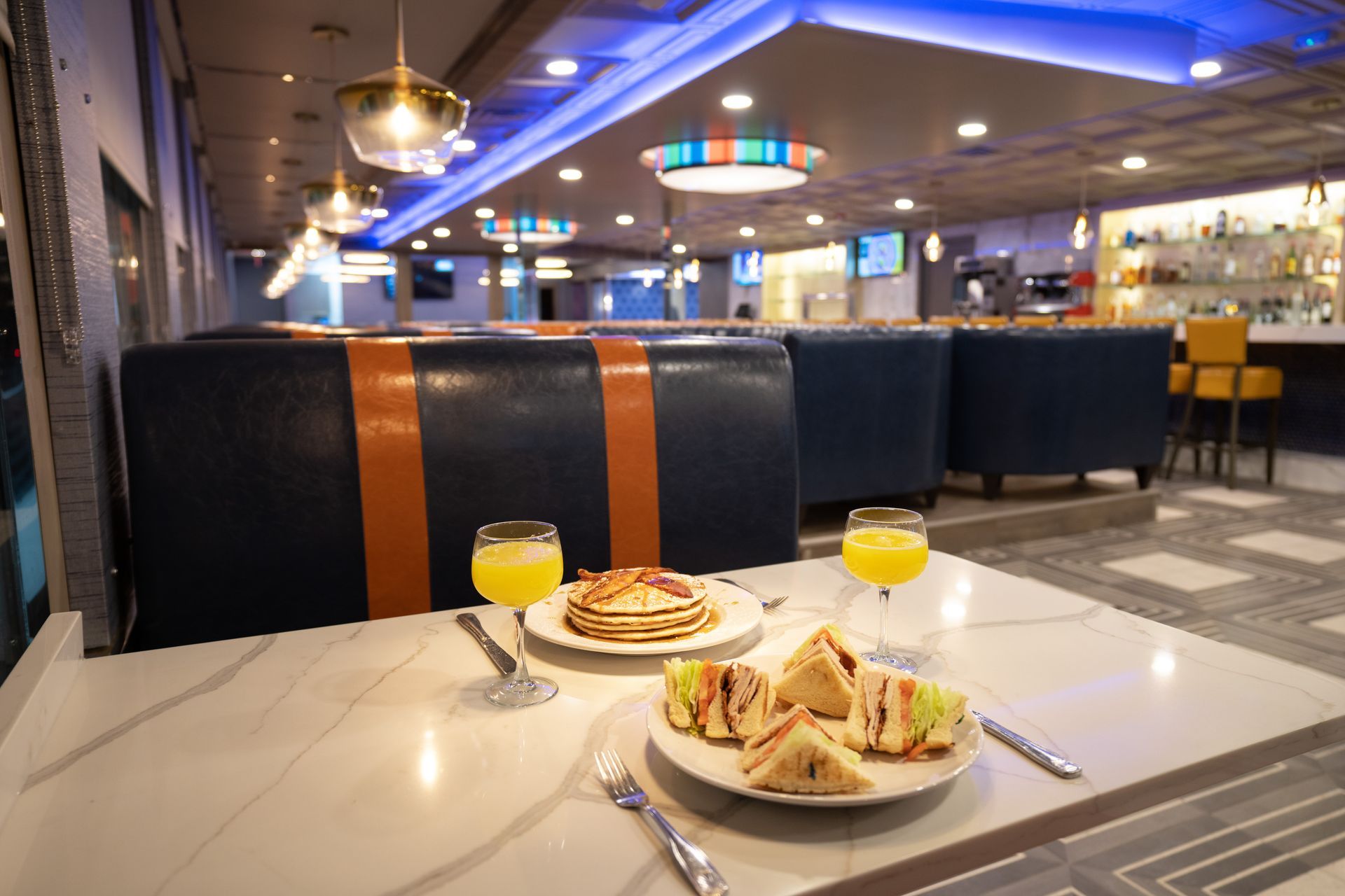 A table with a plate of food and two glasses of orange juice.