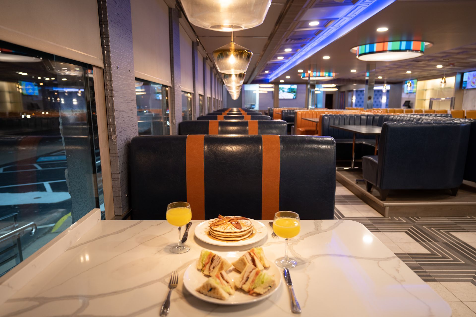 A diner with plates of food and glasses of orange juice on a table.