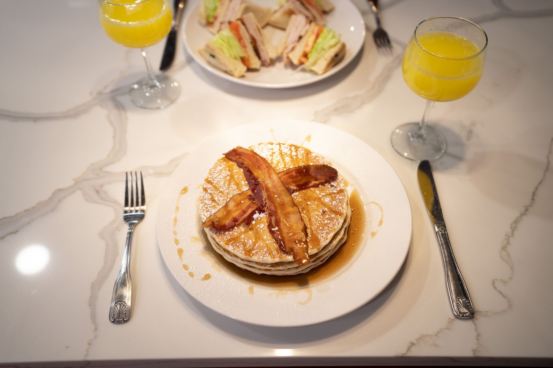 A plate of pancakes with bacon and syrup on a table