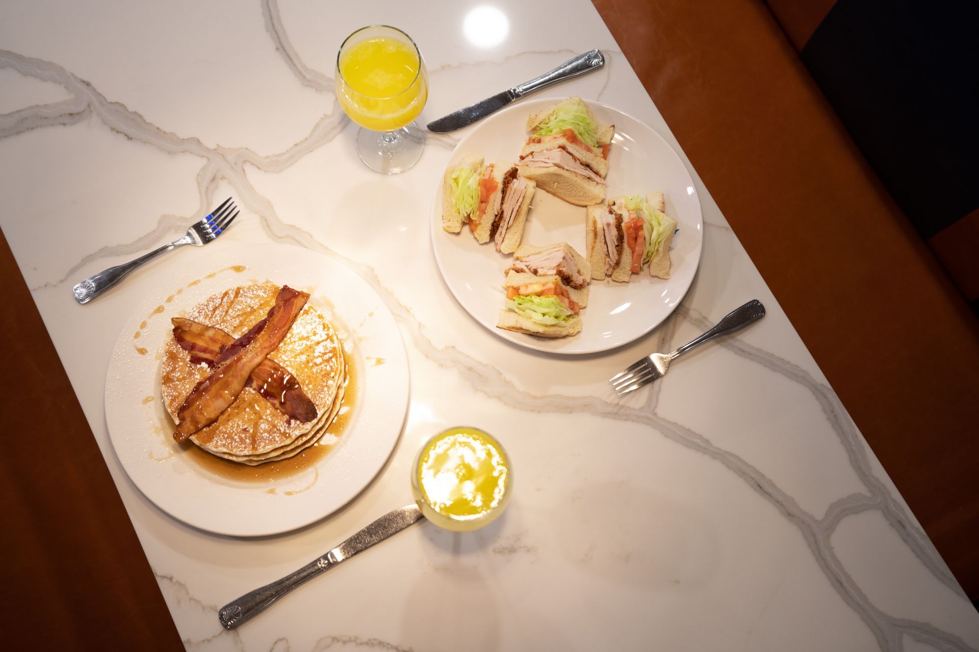 A table topped with plates of food and a glass of orange juice.