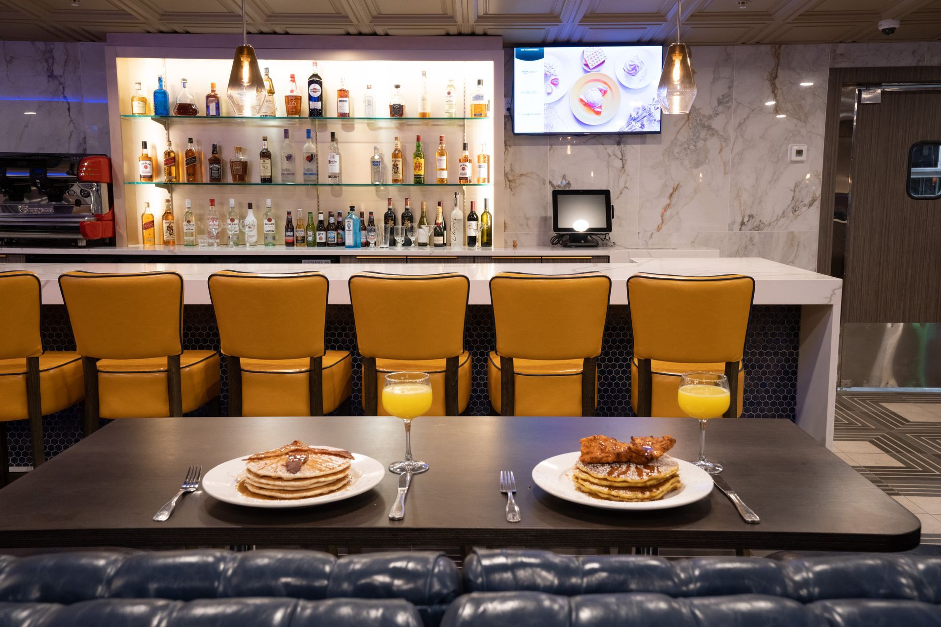There are two plates of food on the table in front of a bar.
