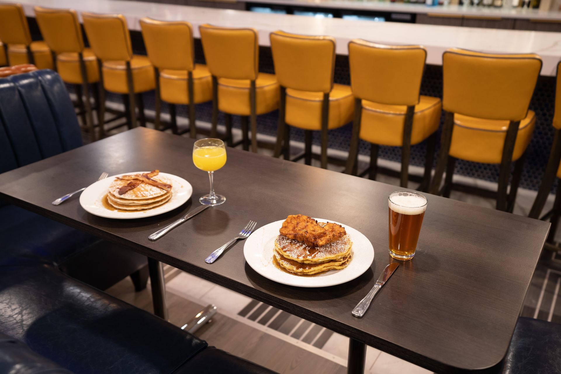 A table with two plates of food and a glass of orange juice on it.
