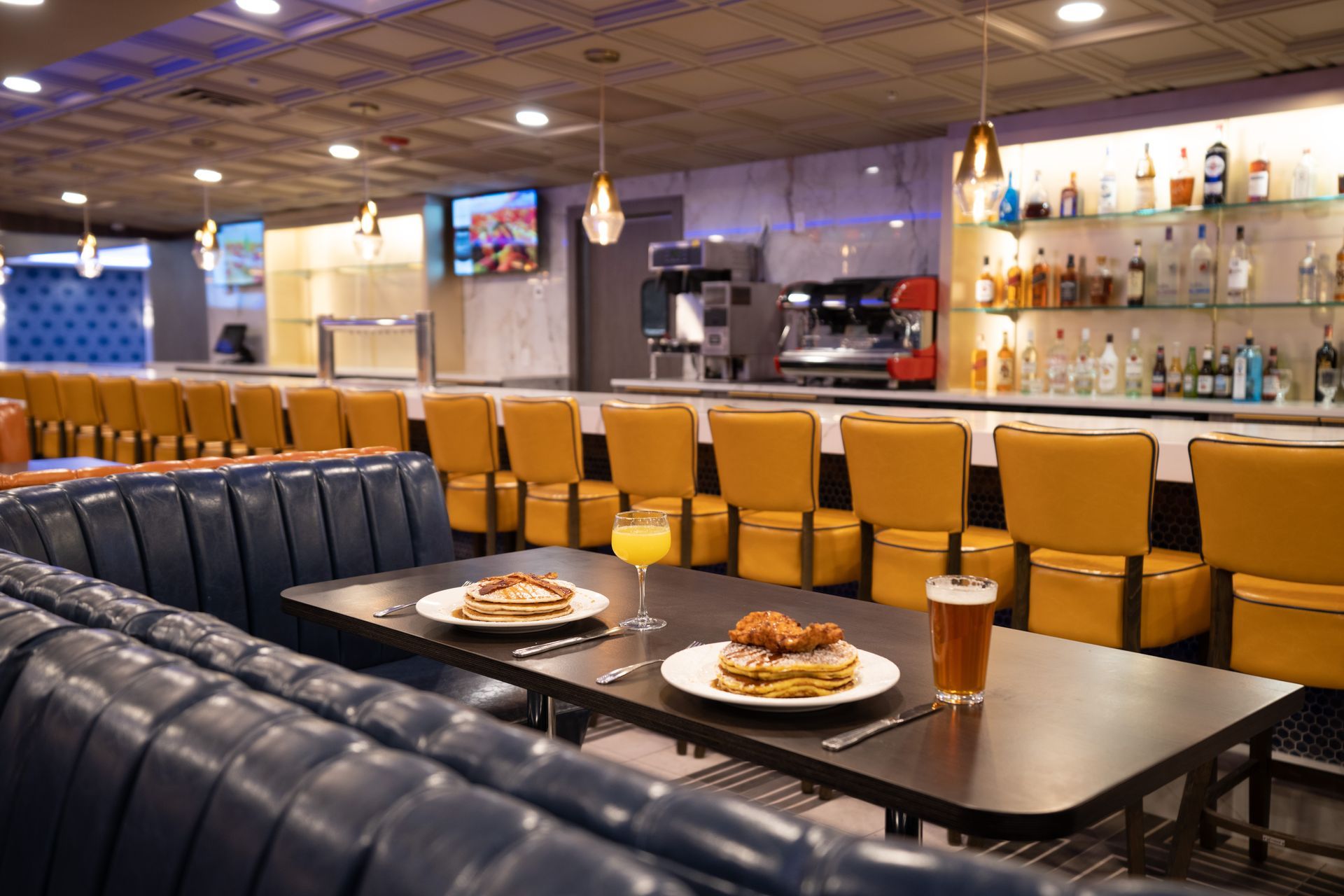 A diner with a table with pancakes and a glass of beer on it.