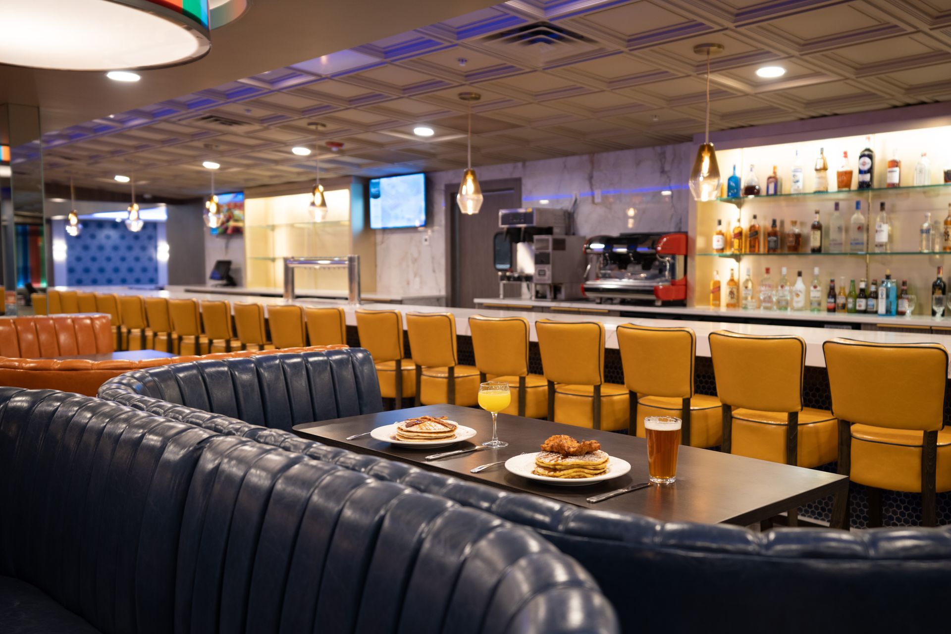 A restaurant with tables and chairs and a bar.