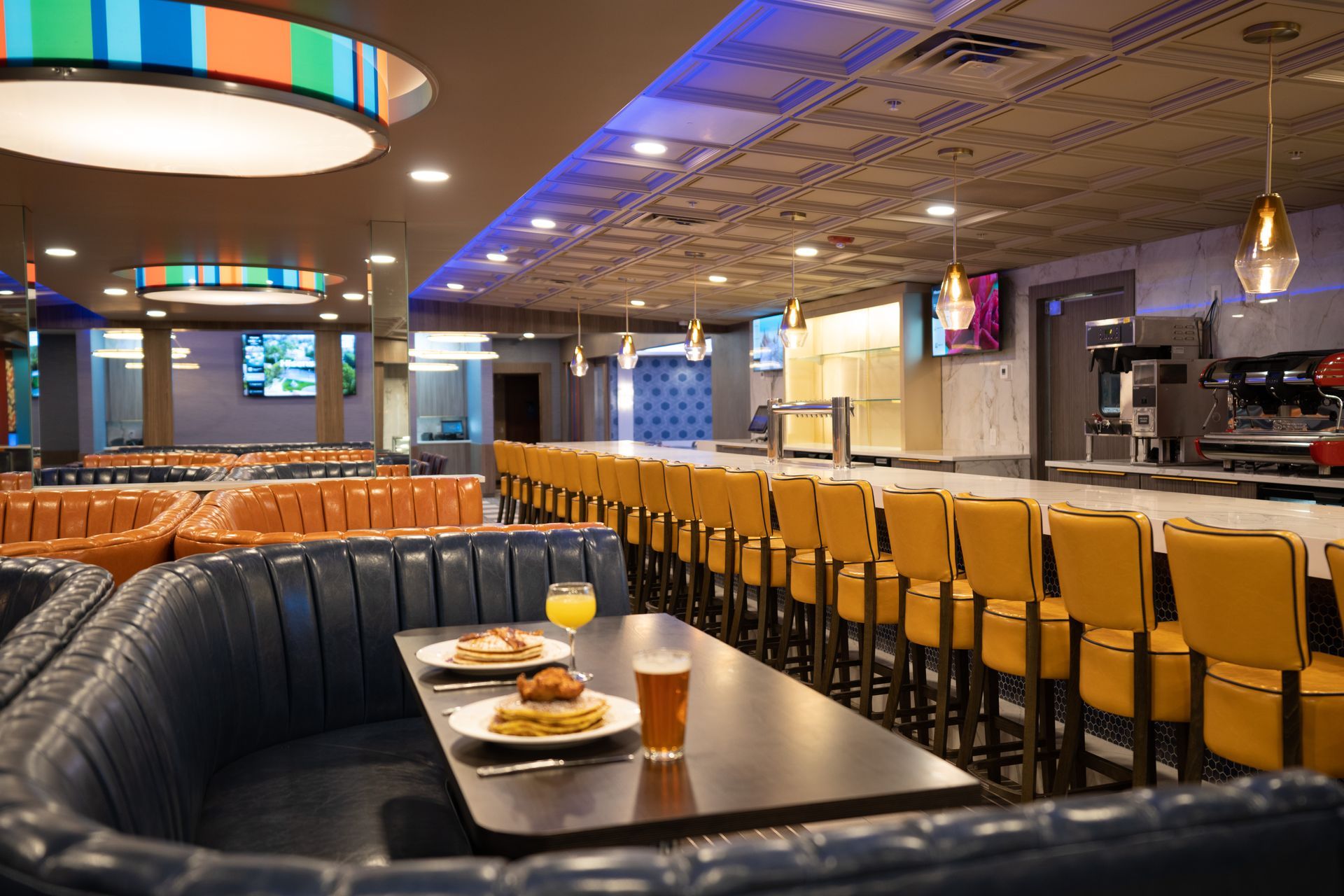 A restaurant with a long bar and tables with plates of food on them.
