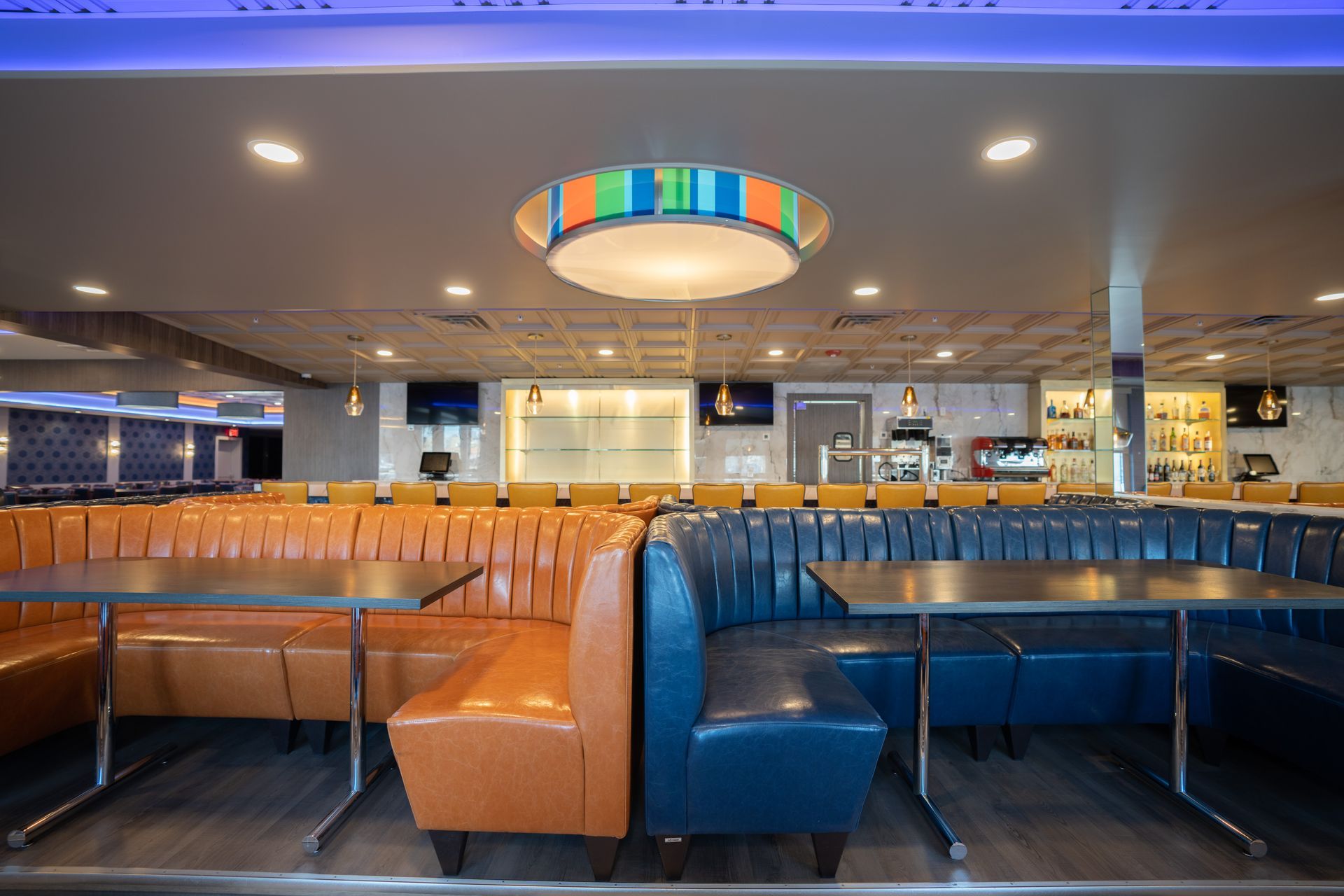 A restaurant with tables and benches and a chandelier on the ceiling.